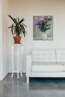 Canvas przedstawiający kolorowe kwiaty w wazonie powieszony nad białą sofą w salonie
