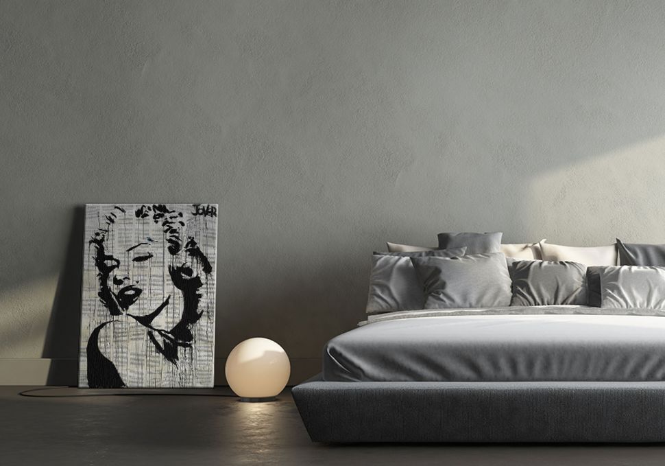 Obraz na płótnie z wizerunkiem Marilyn Monroe stojący obok lampki nocnej i łóżka oparty o ścianę