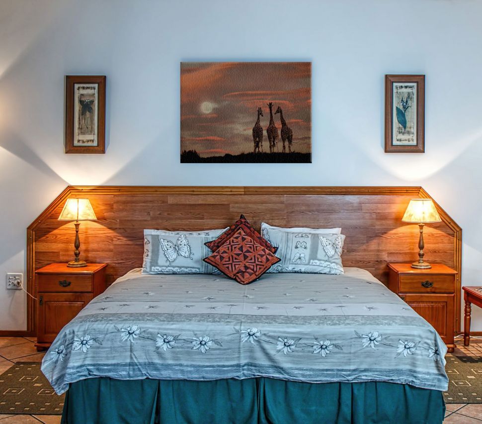 Zdjęcie pokazujące obraz na płótnie z żyrafami wiszący w stylowej sypialni nad łóżkiem